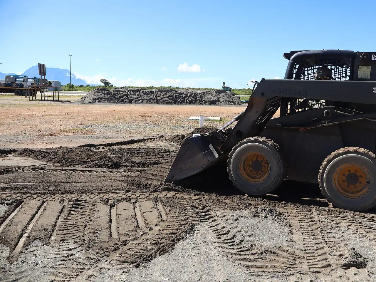 A compact track loader grading a cleared area of ground