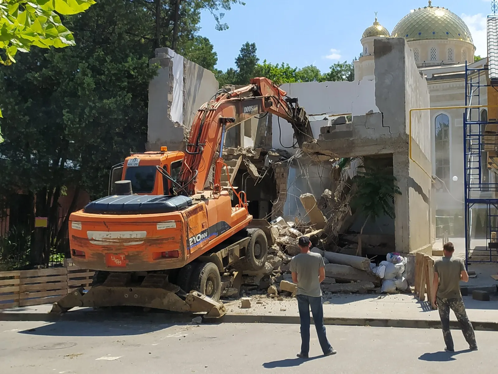 An excavator breaking up a structure into rubble during demolition